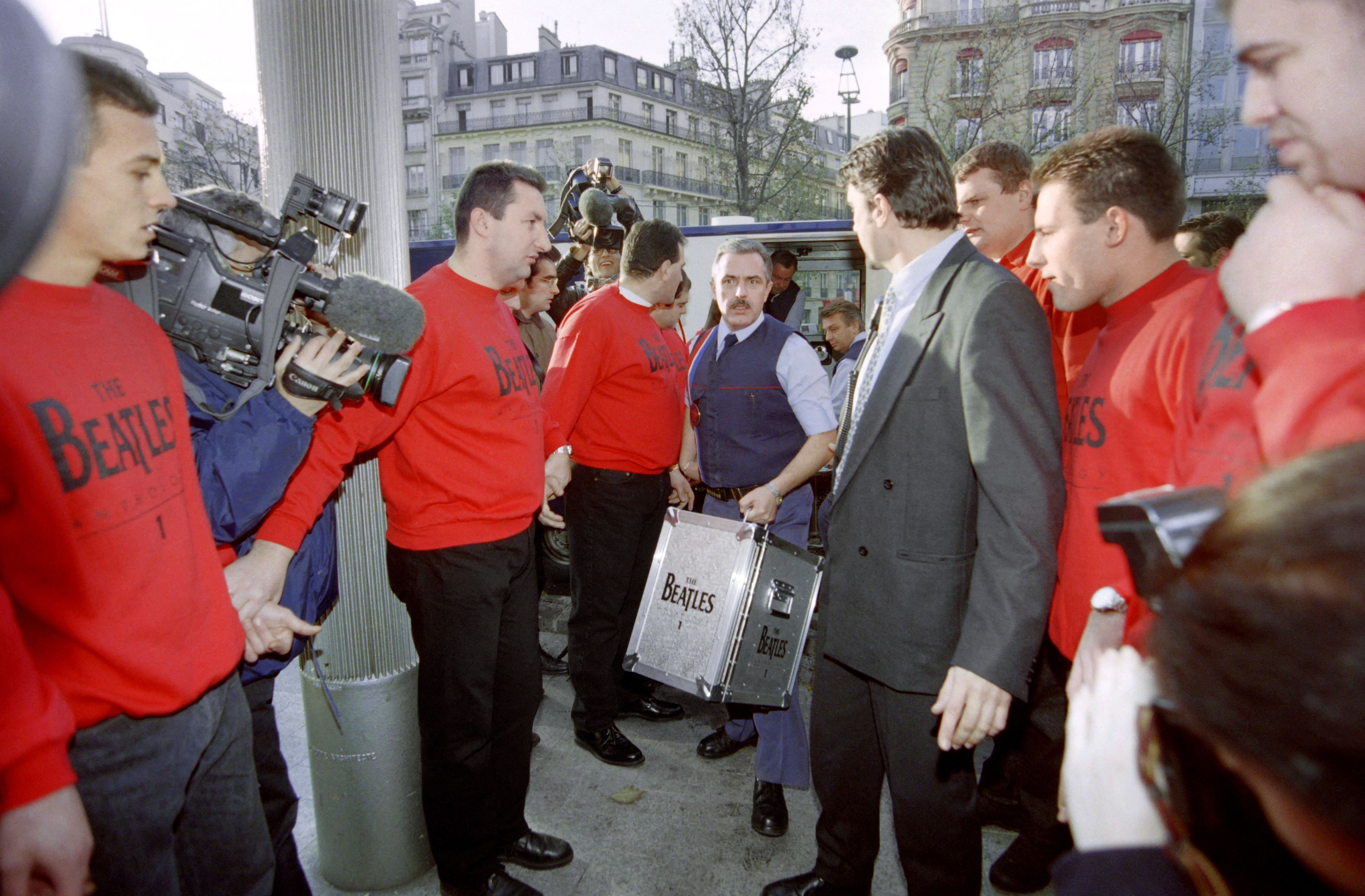 เจ้าหน้าที่รักษาความปลอดภัยขนแผ่นซีดีอัลบั้ม The Beatles Anthology 1 ให้ร้านขายแผ่นเสียงแห่งหนึ่งในกรุงปารีส เมื่อเดือนพฤศจิกายน 1995 (ภาพ: Michel Gangne/AFP)