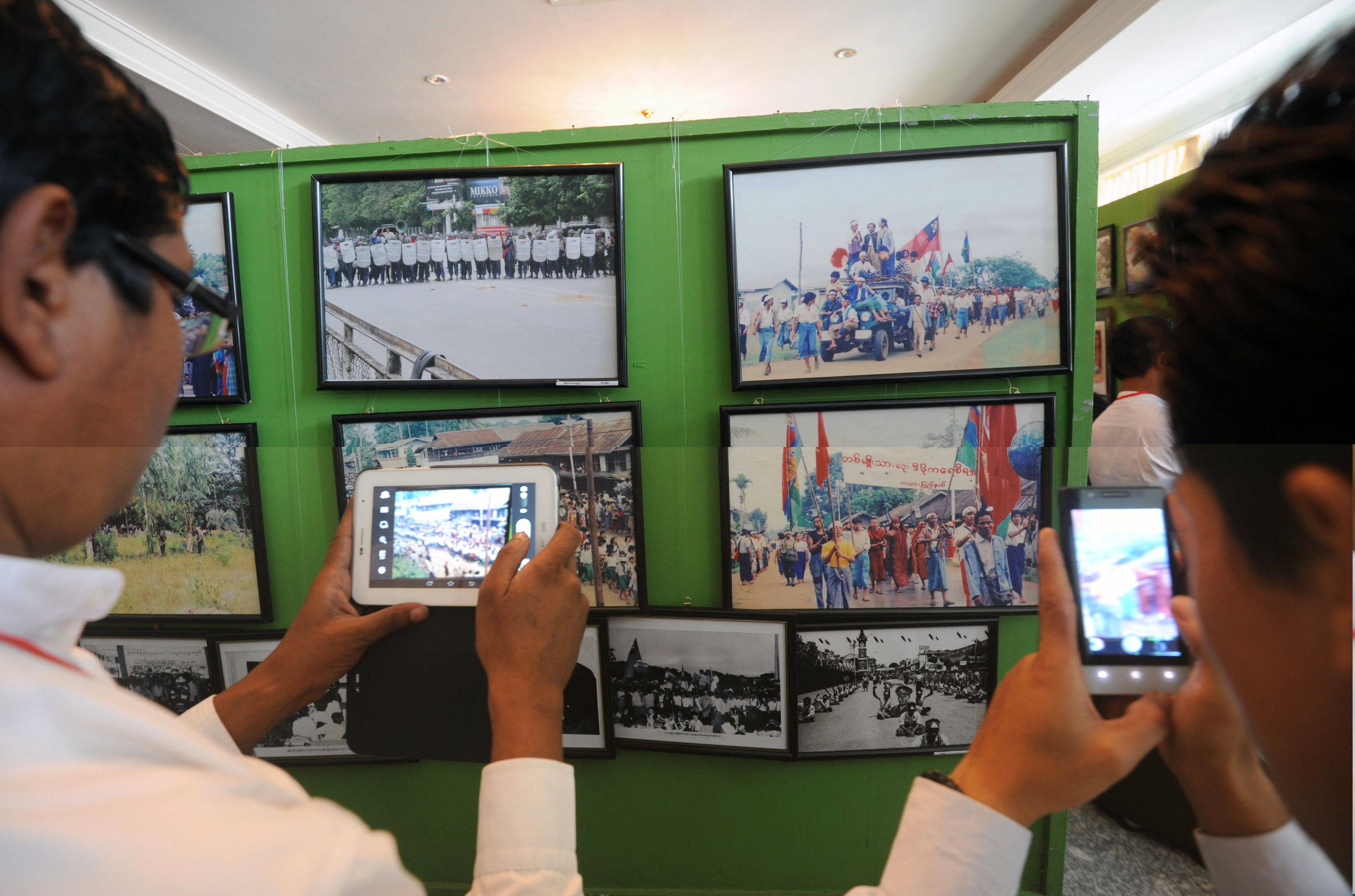ผู้เยี่ยมชมกำลังถ่ายรูปในนิทรรศการครบรอบ 25 ปีการลุกฮือ 8888 ที่ย่างกุ้ง (ภาพจาก: Soe Than Win/AFP)