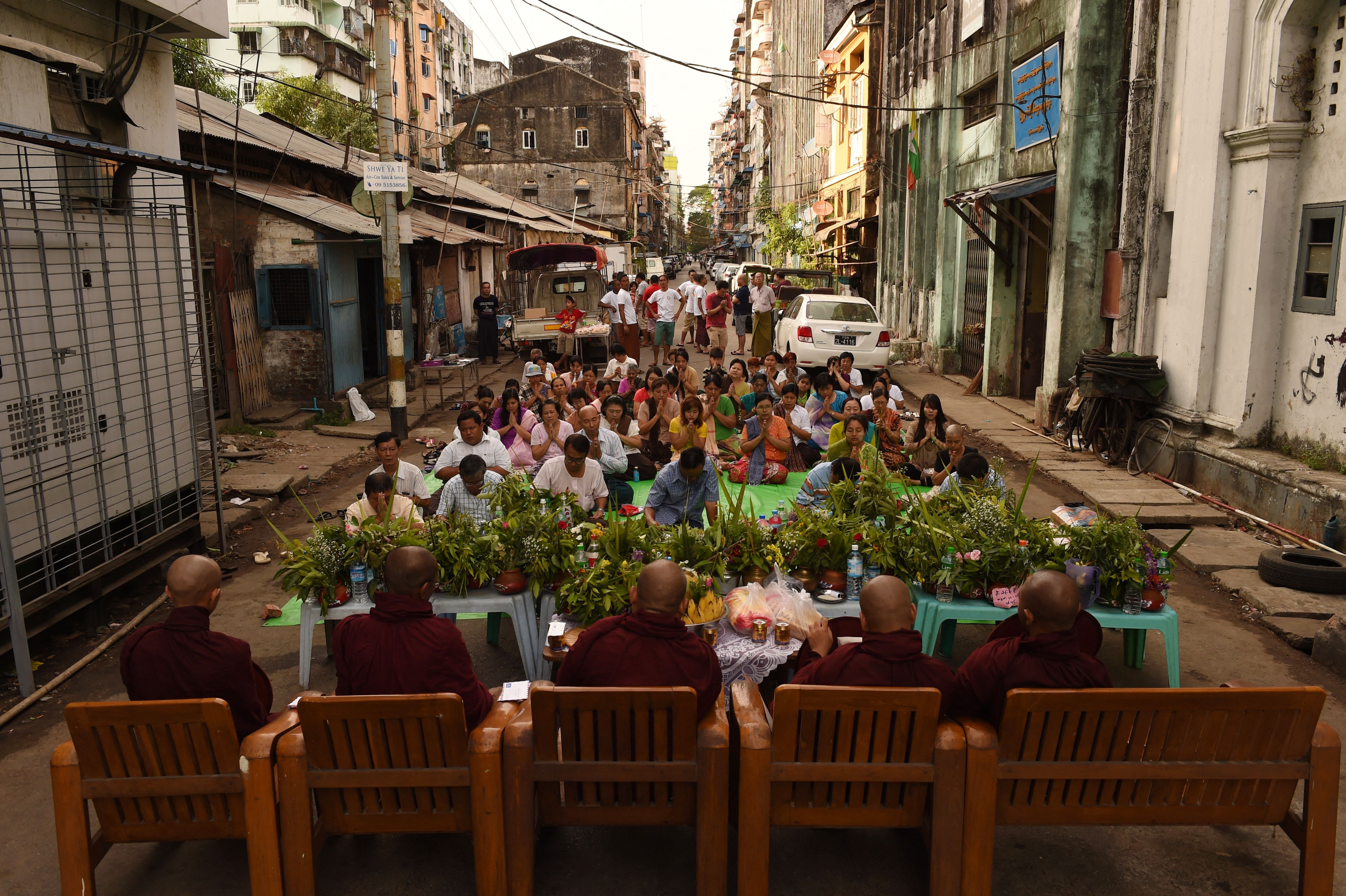 พุทธศาสนิกชนในกรุงย่างกุ้งทำบุญแด่พระสงฆ์เนื่องในเทศกาลตะจาน โดยมีอะตาโอห์วางอยู่ด้านหน้า เมื่อปี 2559 (ภาพ: Romeo Gacad/AFP)