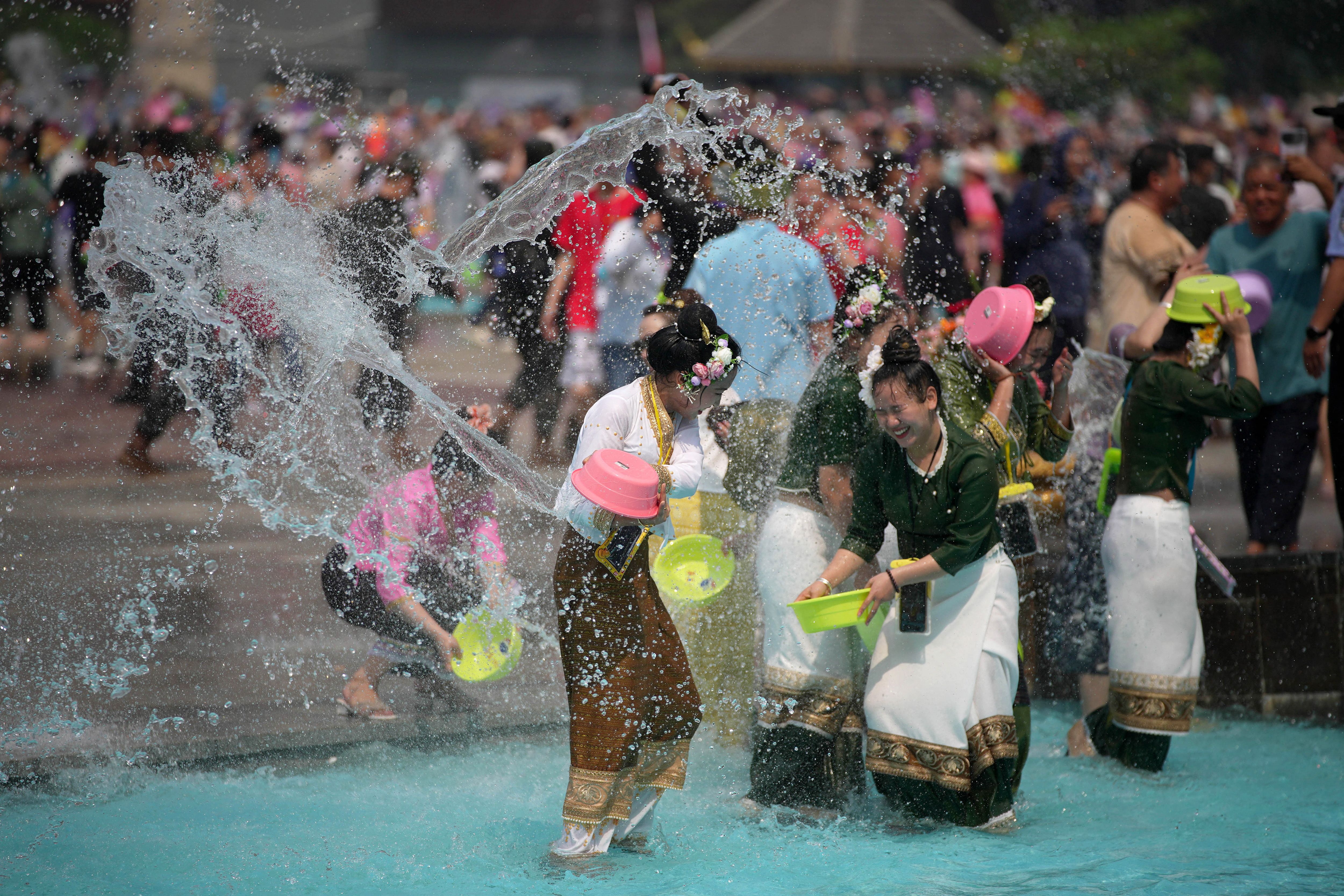 สงกรานต์ในเชียงรุ่ง เมื่อปี 2566 มีชาวไทลื้อสวมชุดประจำชนชาติเล่นน้ำ (ภาพ: CN-STR/AFP)