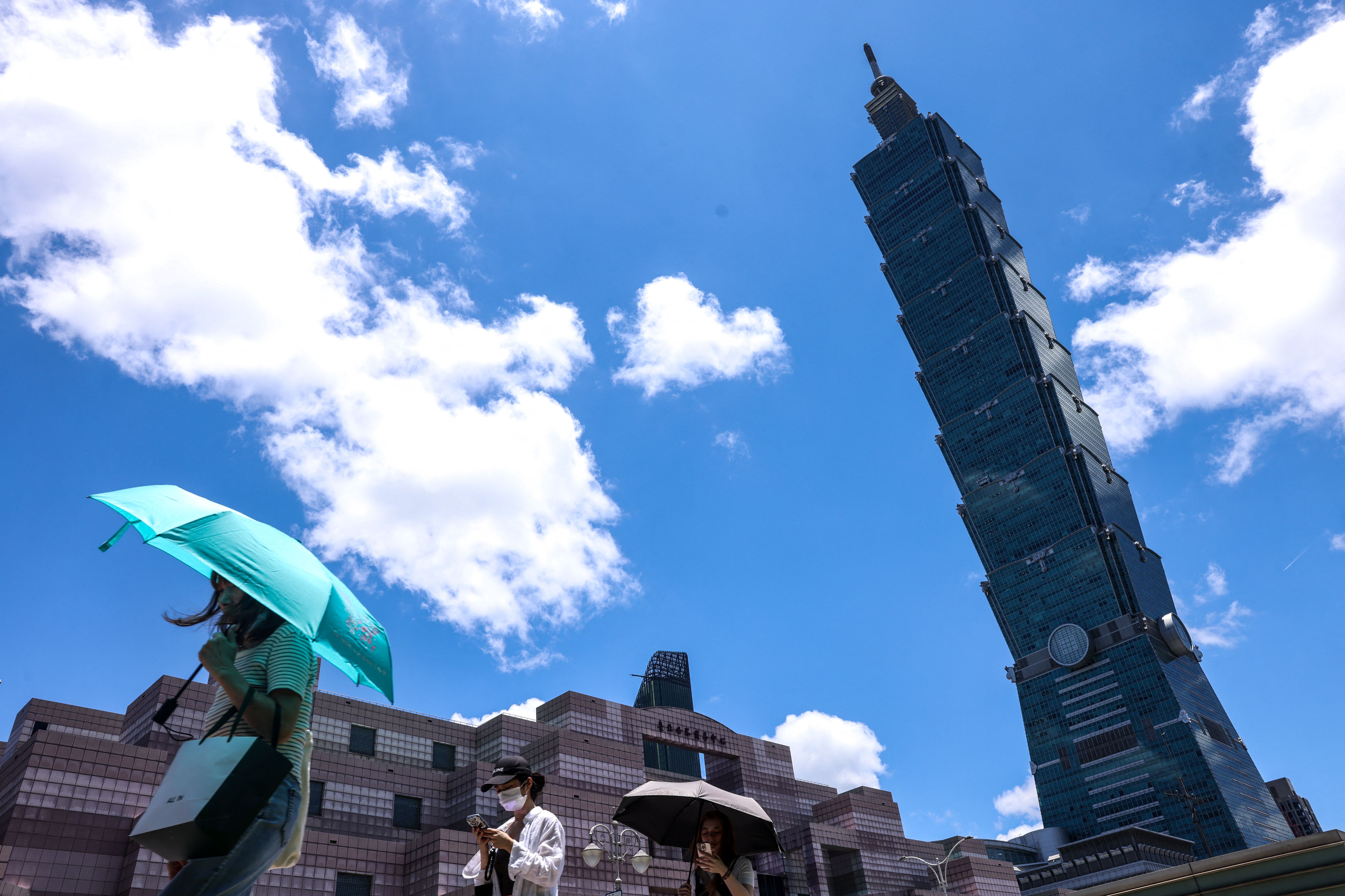 ผู้คนใกล้ตึก Taipei 101 เดินกางร่มท่ามกลางอากาศร้อนในเดือน ก.ค. 68 (ภาพจาก: I-Hwa Cheng/AFP)