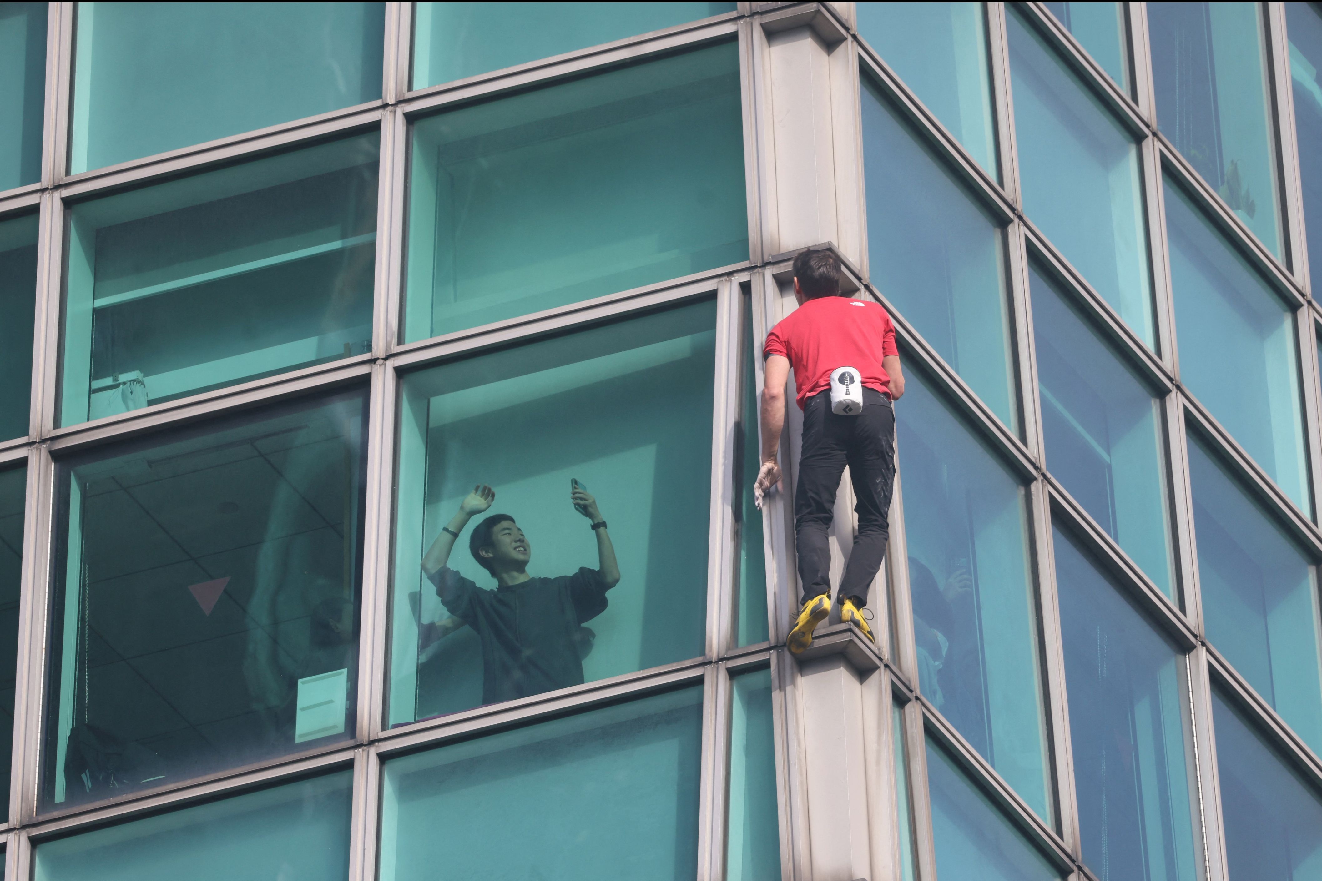ชายคนหนึ่งบนตึก Taipei 101 กำลังถ่ายภาพ Alex Honnold (ภาพ: I-Hwa Cheng/AFP)