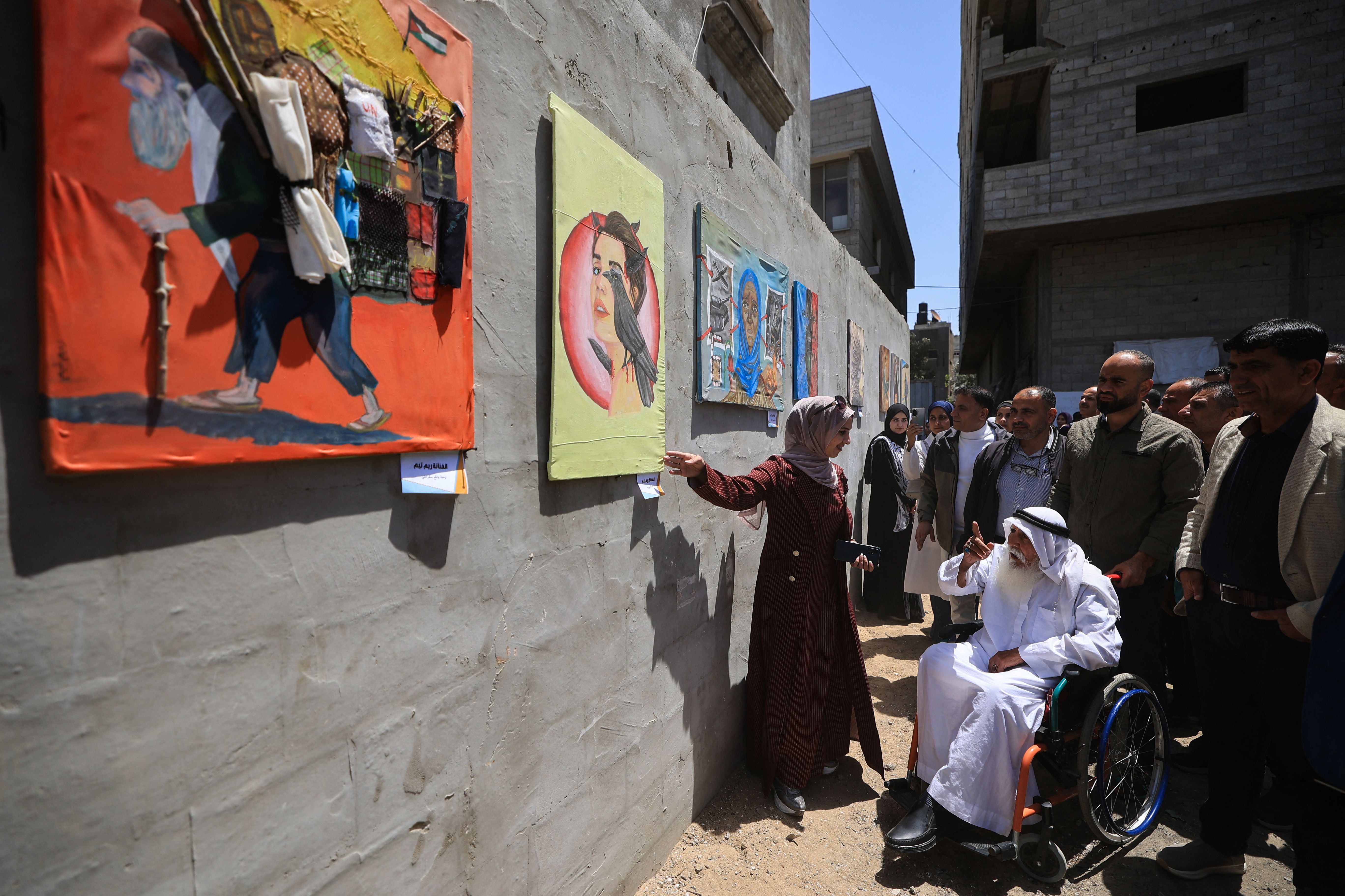 รีม ทาอิม (กลาง) ศิลปินในฉนวนกาซา ขณะพูดคุยกับผู้เยี่ยมชมผลงาน (ภาพ: Eyad Baba/AFP)