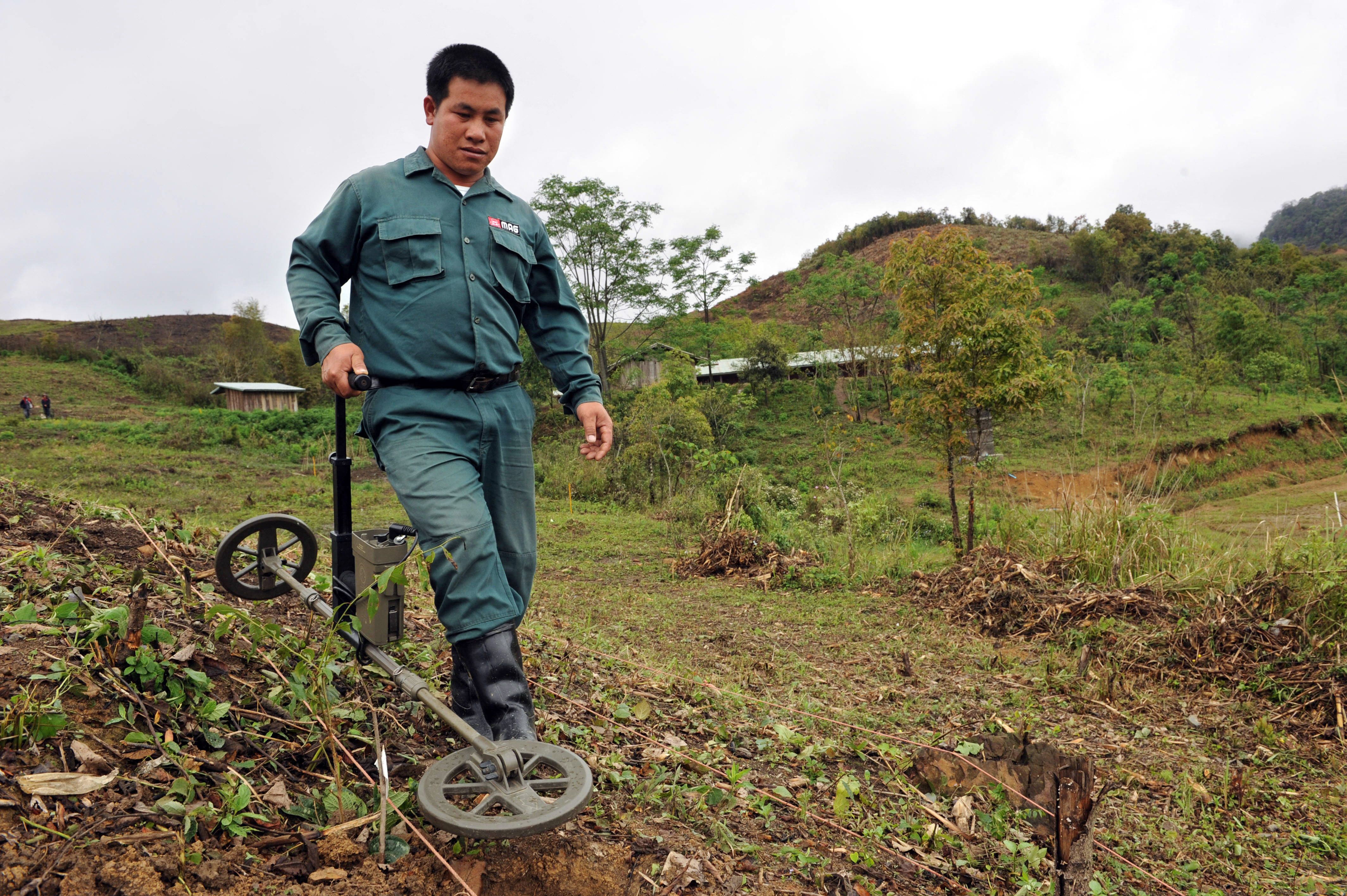 การใช้เครื่องตรวจจับโลหะค้นหาระเบิด (Photo by HOANG DINH NAM/AFP)