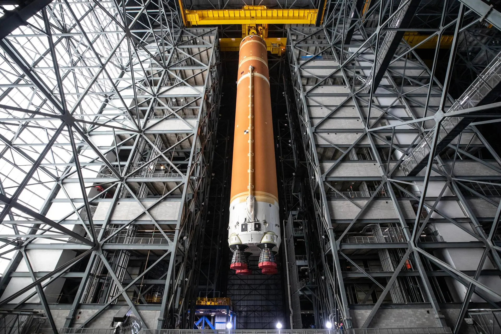 ภาพถ่ายท่อนจรวดหลักของจรวด SLS ถูกยกขึ้นด้วยเครนภายในอาคาร VAB เพื่อทำการประกอบกับชิ้นส่วนอื่นของจรวด ภาพจาก NASA