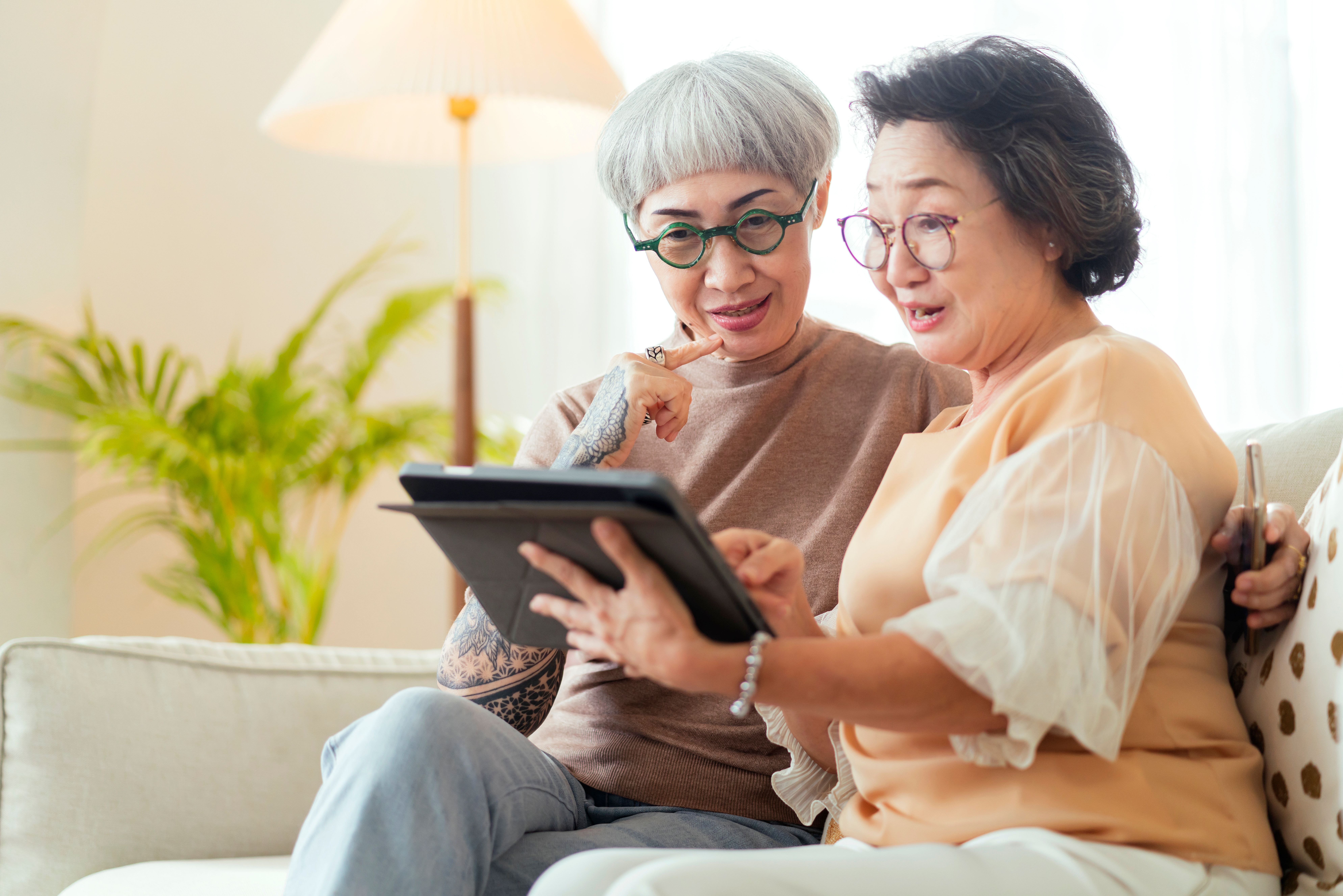visit-house-two-senior-old-mature-female-friends-looking-through-old-photos-digital-album-together-with-tablet-device